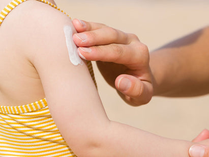 sunscreen being applied to a toddlers arm