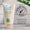 En hvit tube Organic Babies Baby Wash & Shampoo Scent Free står ved siden av en Dermatologisk Testet-logo mot en hvit flislagt vegg.