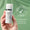 En hånd holder en flaske Age Defy+ Tinted DD Moisturiser SPF 15 mot grønn bakgrunn med et dermatologisk testet-stempel.