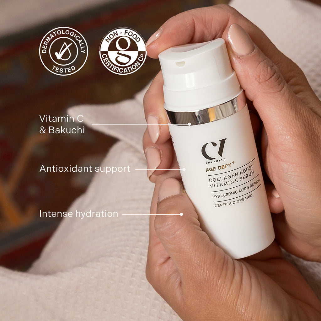 Hender holder flasken med Age Defy+ Collagen Boost Vitamin C Serum, og fremhever dens naturlige formel, antioksidanter og intense fuktighet.