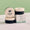 Tre runde svarte og beige Green People ONE Balm-bokser, utstilt sammen med produktesken på en marmorflate.