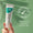 En hånd holder en tube Oy Clear Skin Purifying Serum mot en myk grønn bakgrunn med et "dermatologisk testet"-merke.